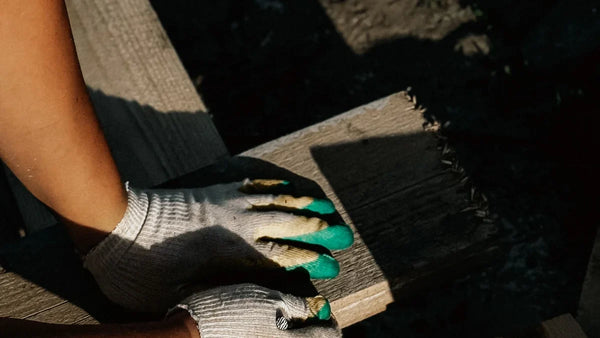 Main gantée posée à plat sur une planche en bois, en extérieur