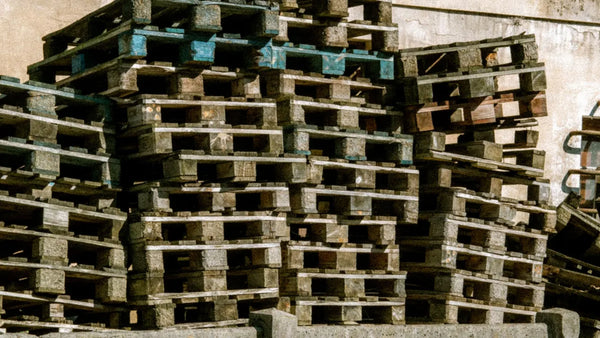 Pile de palettes en bois empilées à l'extérieur, prêtes à être récupérées